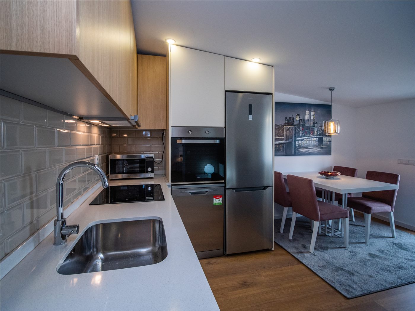 Cozinha renovada com bancada clara, eletrodomésticos integrados e zona de refeição