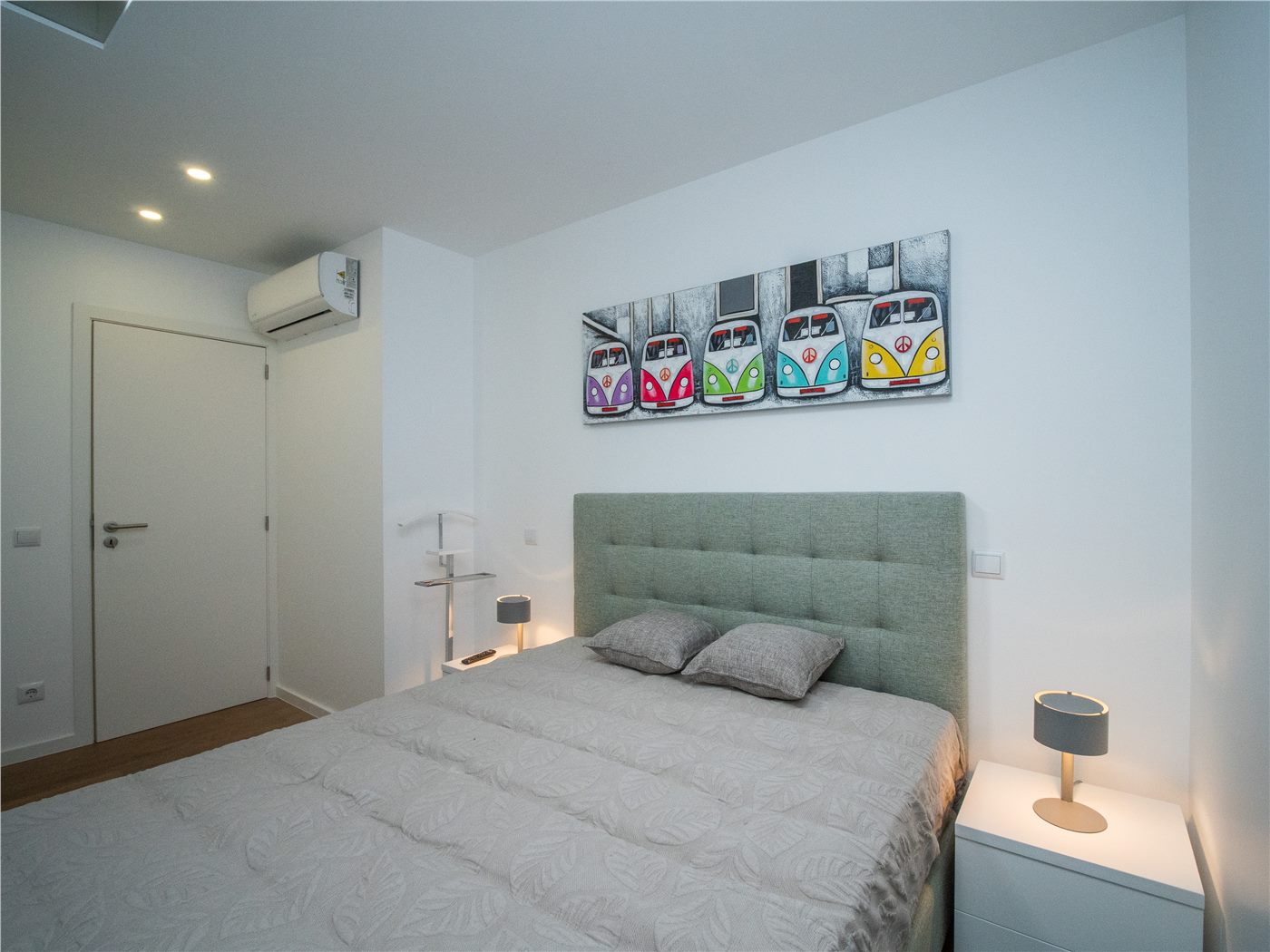 Quarto renovado com cabeceira estofada, iluminação de apoio e ambiente neutro